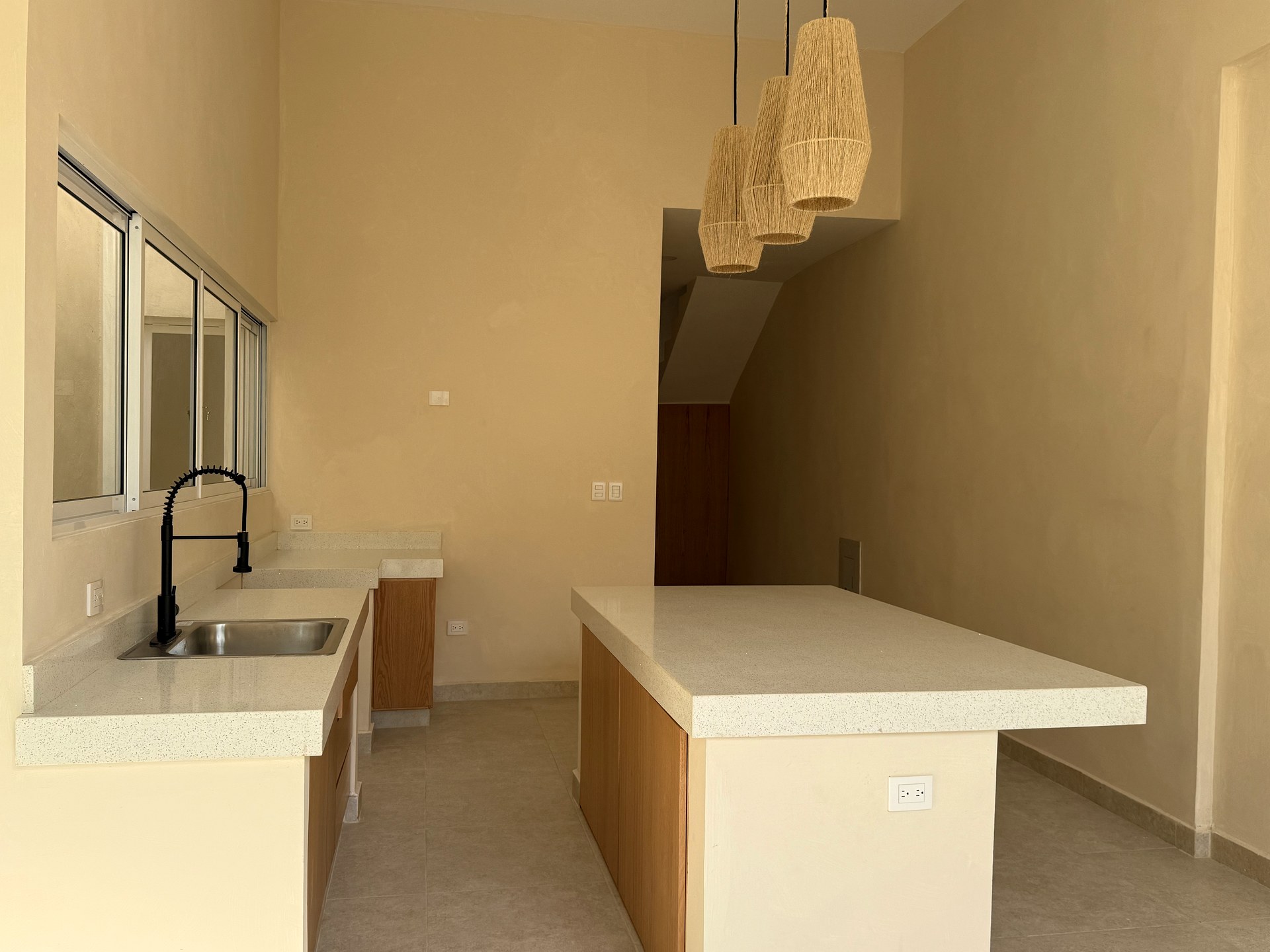 Casa Suspiro — modern open kitchen with island, pendant lights, and natural wood cabinetry