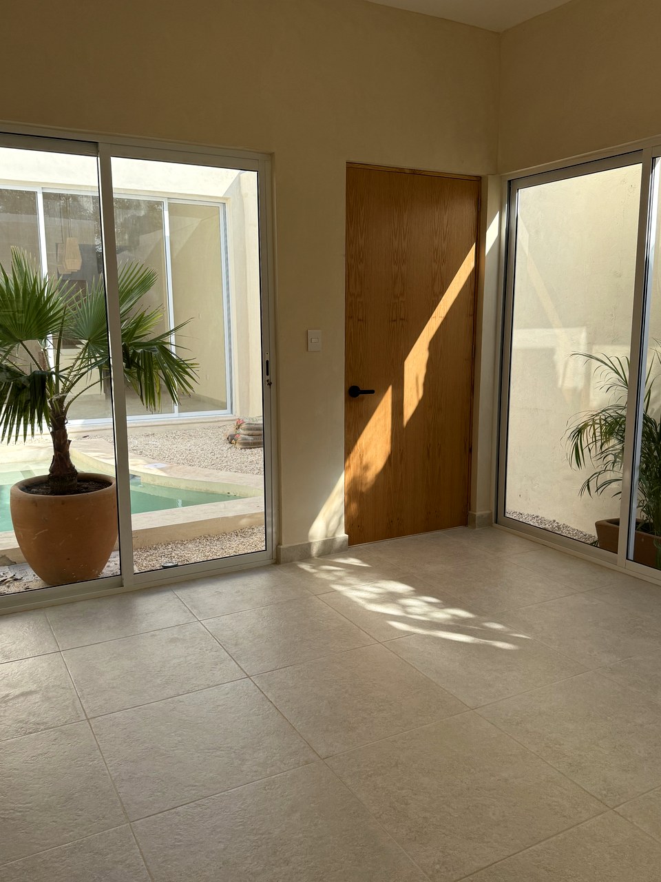 Casa Suspiro — living area with floor-to-ceiling glass doors opening to pool courtyard